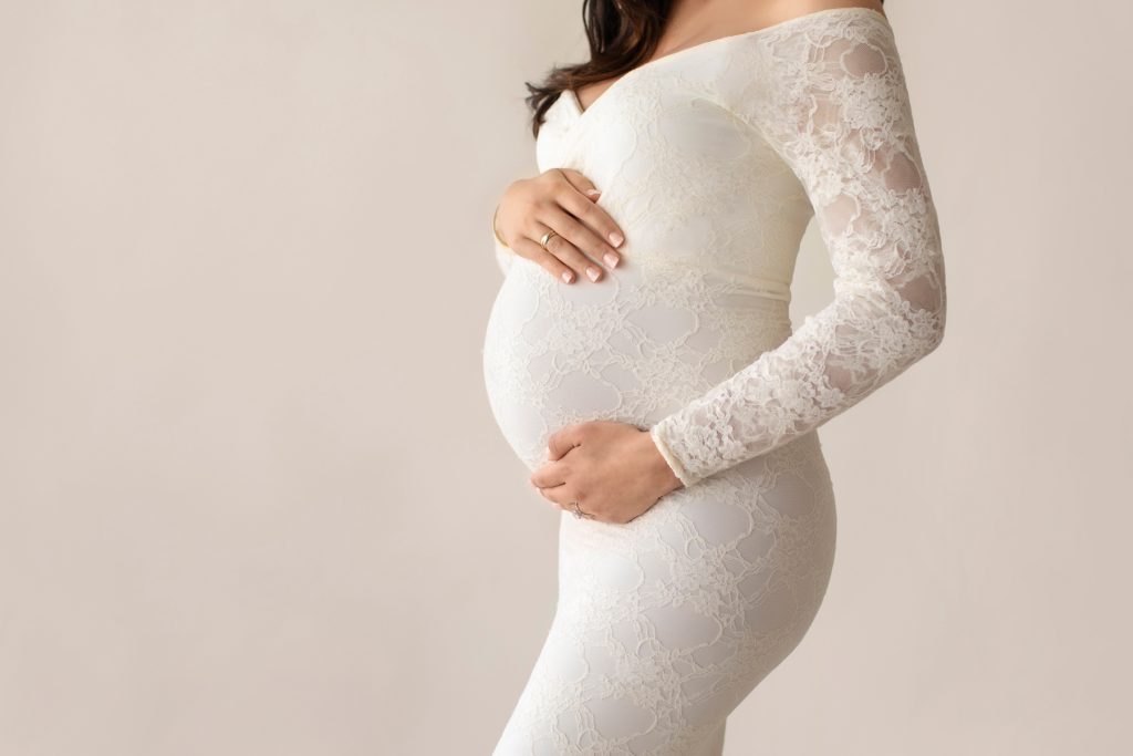 Gorgeous pregnant mom dressed in long sleeved ivory lace mermaid maternity gown close up profile photo
