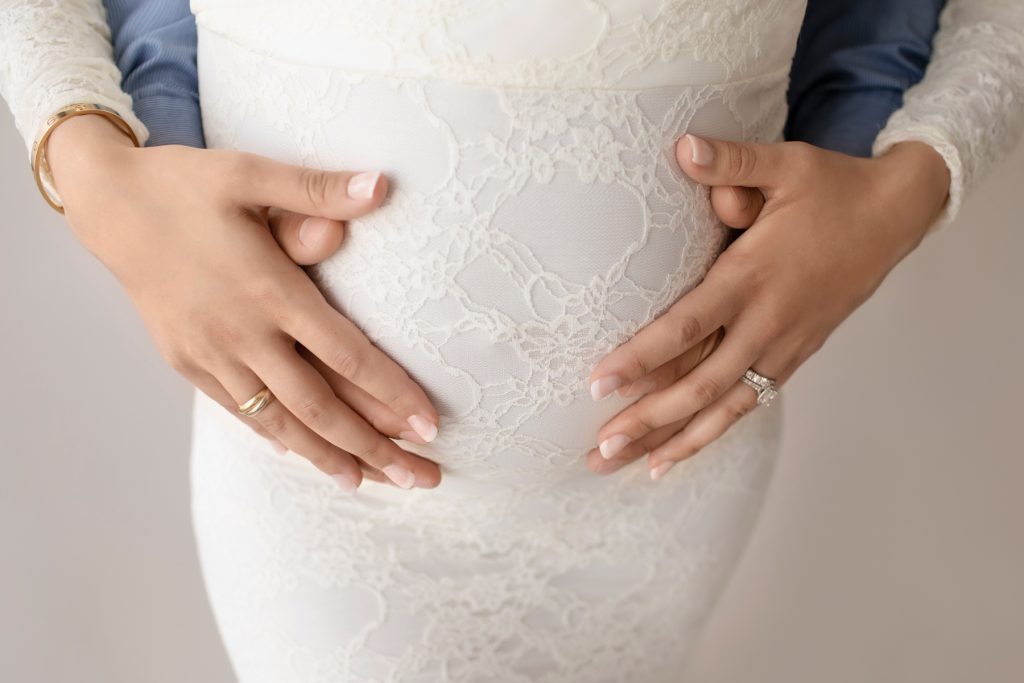 Pregnant mom dressed in long sleeved ivory lace mermaid maternity holding beautiful belly belly with dad