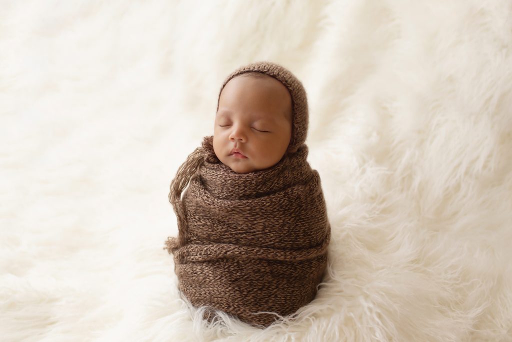 Lucas baby newborn wrapped like a brown potato sack with matching knit bonnet