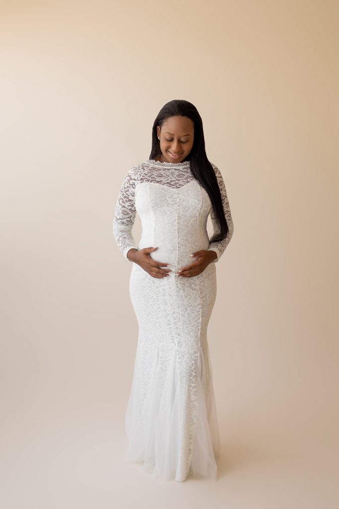 christine white lace maternity gown expectant mama looks down on baby bump