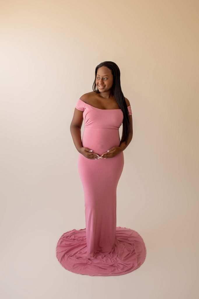 christine deep pink maternity gown expectant mama holds her baby bump looks out window