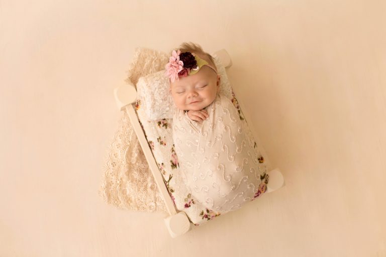 mini newborn photo session girl in ivory lace on floral bed floral headtie Gainesville FL