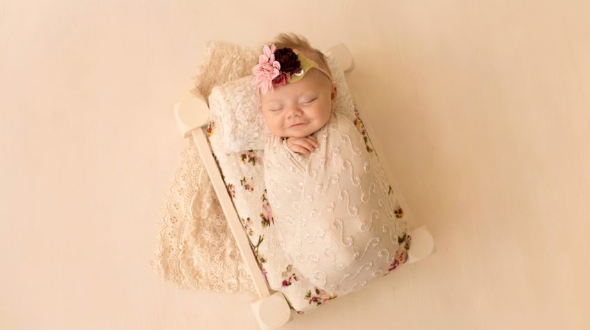 mini newborn photo session girl in ivory lace on floral bed floral headtie Gainesville FL