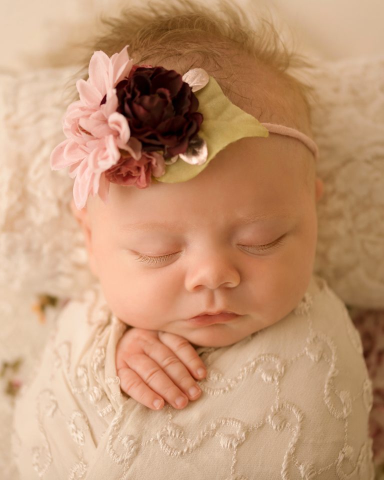 mini newborn photo session girl close up gorgeous eyelashes tiny baby fingers ivory lace on floral bed floral headtie Gainesville FL