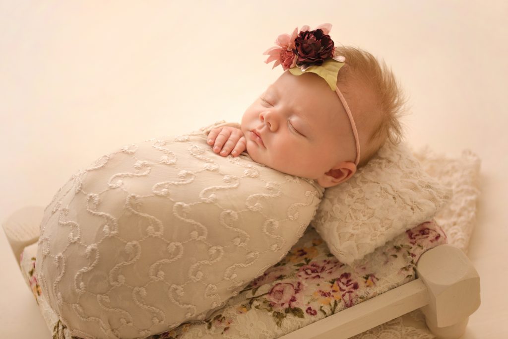 mini newborn photo session girl ivory lace on floral bed floral headtie