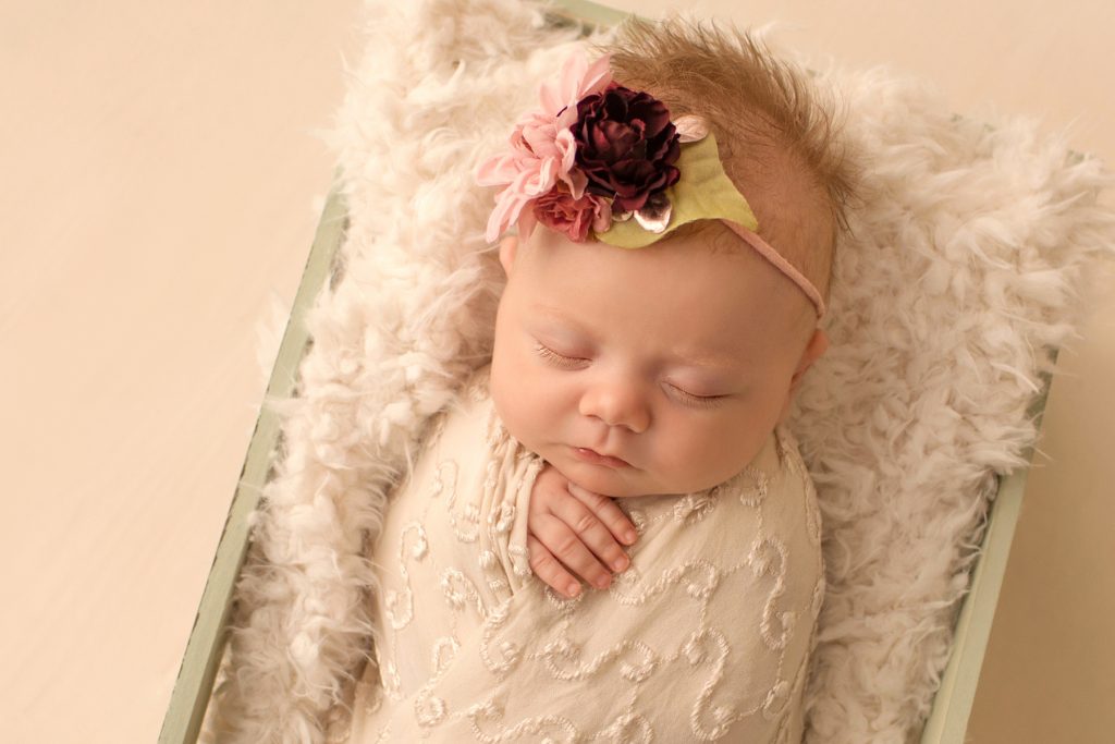 newborn photo session girl close up beautiful baby face gorgeous eye lashes ivory lace in sea green wooden crate floral headtie Gainesville FL