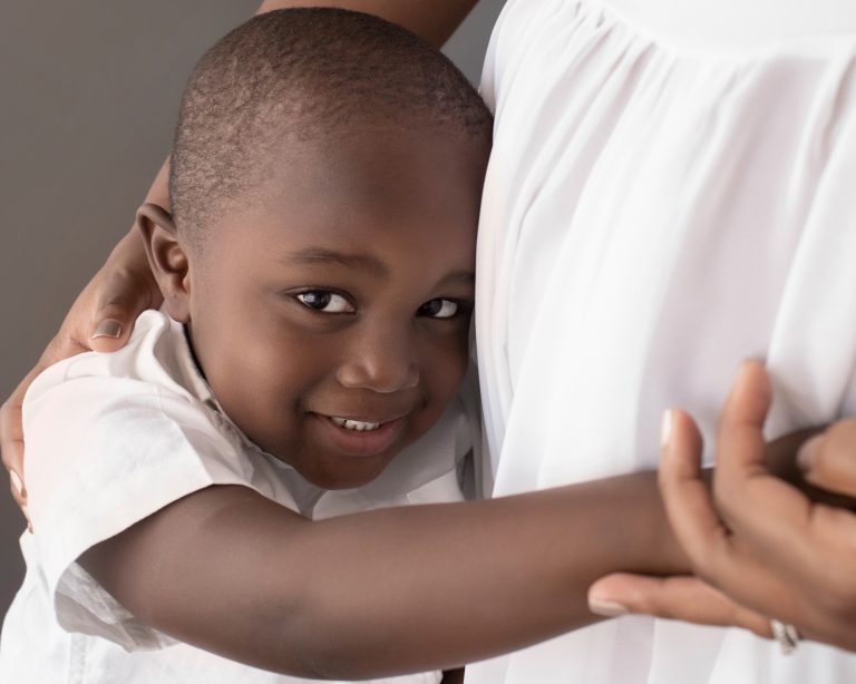 boy big eyes smile hugs moms pregnant belly maternity portrait