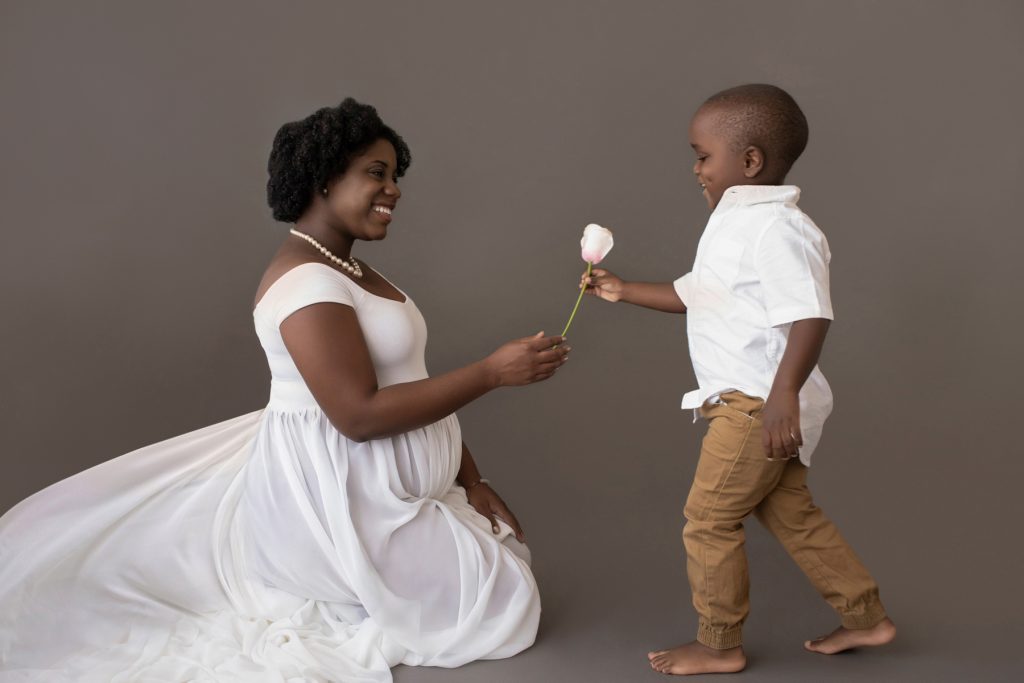 boy hands pink rose for newborn sister to pregnant mom white chiffon toss maternity gown