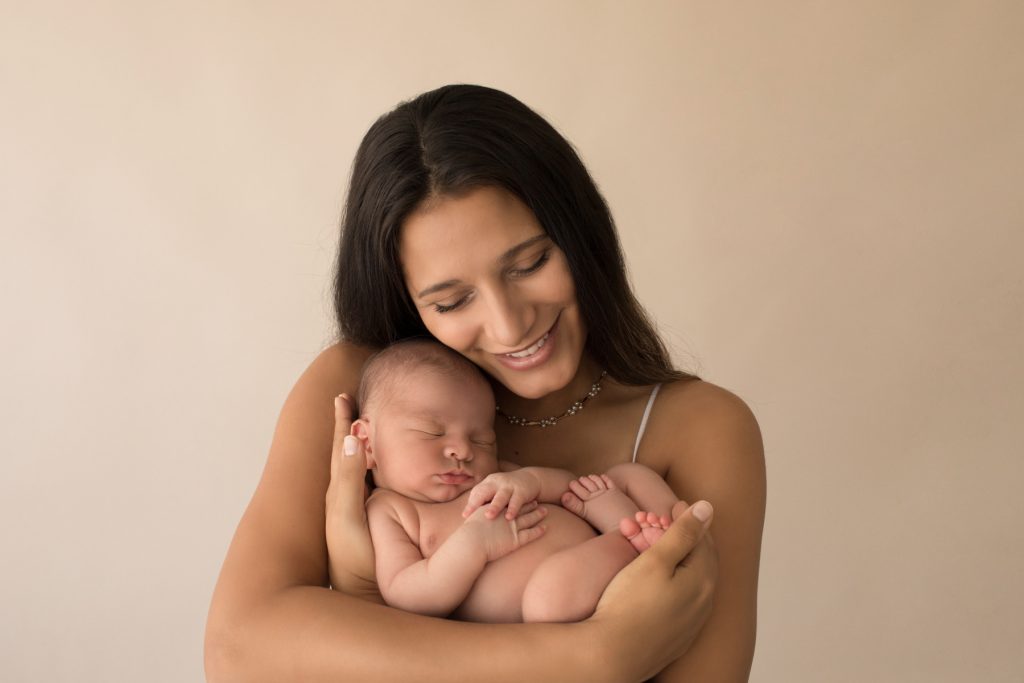Gorgeous mom cuddles baby boy with affection Gainesville FL newborn mini photo session