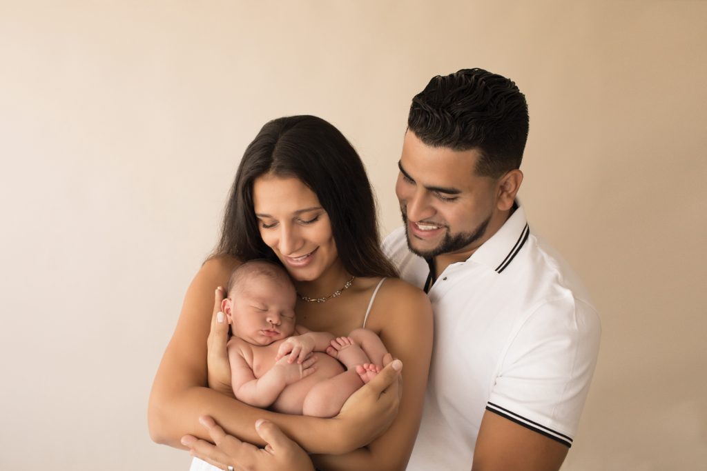 Smiling new mom and dad cuddle baby boy in first family portrait Gainesville FL