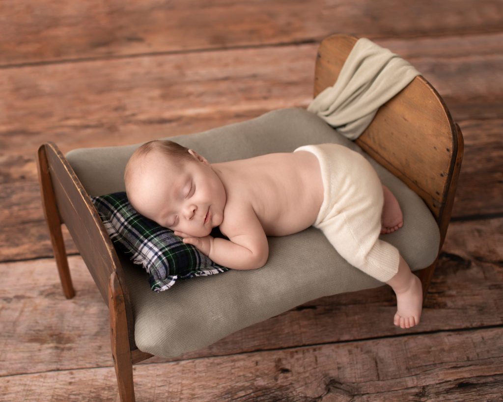 baby grin boy sleeps in antique wood bed green plaid pillow Gainesville FL newborn photos