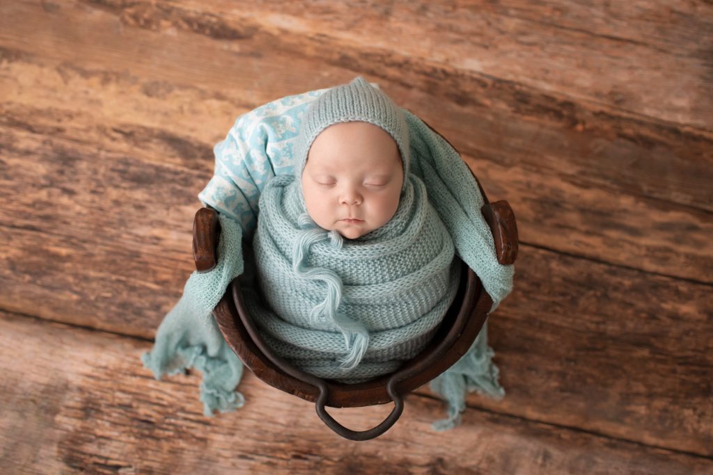 baby boy in wood bucket blue knit potato sack matching bonnet Gainesville FL newborn photos