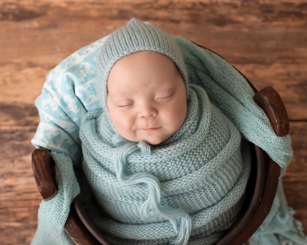 baby boy in wood bucket big smile blue knit potato sack matching bonnet Gainesville FL newborn photos